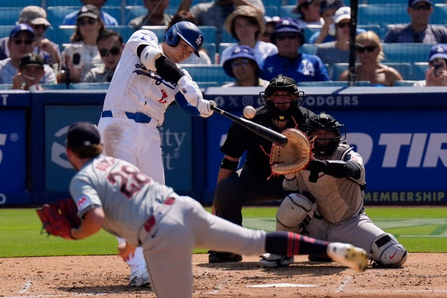 Los Angeles Dodgers' Shohei Ohtani, second from left, hits a solo home run as Cleveland Guardians starting pitcher Tanner Bibee, left, watches along with catcher Bo Naylor, right, and home plate umpire Dan Bellino during the fifth inning of a baseball game, Sunday, Sept. 8, 2024, in Los Angeles. (AP Photo/Mark J. Terrill)