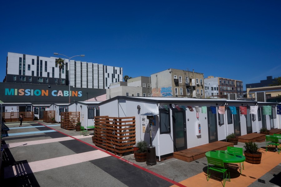 A person walks under a Mission Cabins sign at the Five Keys transitional housing location in San Francisco, Monday, Aug. 26, 2024. (AP Photo/Jeff Chiu)