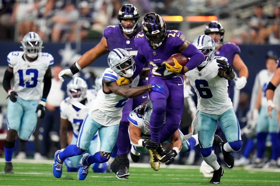 Baltimore Ravens running back Derrick Henry (22) runs the ball as Dallas Cowboys' Jourdan Lewis (2), Eric Kendricks, bottom, and Donovan Wilson (6) attempt to make the stop in the first half of an NFL football game in Arlington, Texas, Sunday, Sept. 22, 2024. (AP Photo/Julio Cortez)