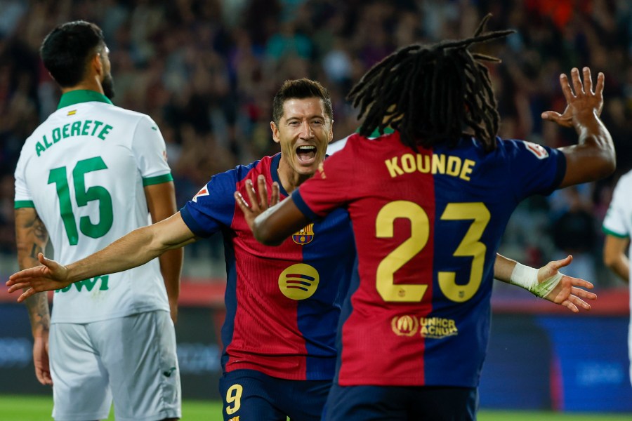 Barcelona's Robert Lewandowski, center, celebrates with Barcelona's Jules Kounde, front, after scoring the opening goal during a Spanish La Liga soccer match between Barcelona and Getafe at the Olympic stadium in Barcelona, Spain, Wednesday, Sept. 25, 2024. (AP Photo/Joan Monfort)