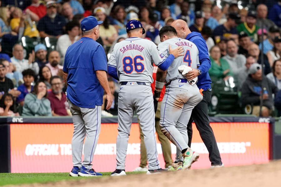 New York Mets' Francisco Alvarez (4) exits the field with coaches and trainers after suffering an injury at third base during the seventh inning of a baseball game against the Milwaukee Brewers, Friday, Sept. 27, 2024, in Milwaukee. (AP Photo/Aaron Gash)