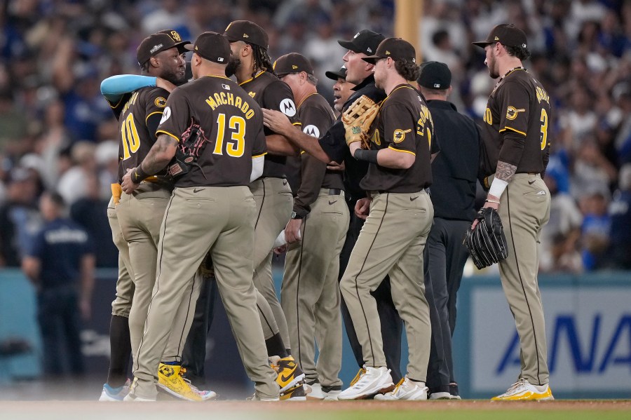 San Diego Padres left fielder Jurickson Profar, left, is held back by teammates after he protested with umpires when items were thrown at him in the outfield during the seventh inning in Game 2 of a baseball NL Division Series against the Los Angeles Dodgers, Sunday, Oct. 6, 2024, in Los Angeles. (AP Photo/Mark J. Terrill)