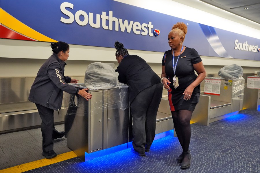 Southwest Airlines employees cover the ticket counters with plastic wrap just before Tampa International Airport was closing due to the possible arrival of Hurricane Milton Tuesday, Oct. 8, 2024, in Tampa, Fla. (AP Photo/Chris O'Meara)