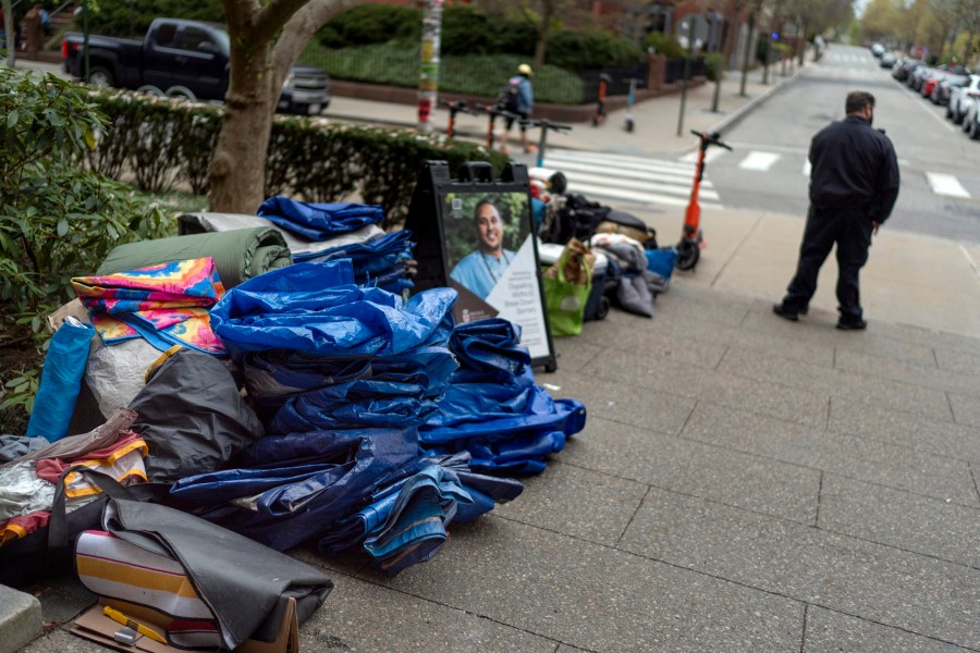 FILE - Tarps, sleeping bags and blankets sit piled on a sidewalk after an encampment protesting the Israel-Hamas war was taken down at Brown University as a campus security officer stands by, Tuesday, April 30, 2024, in Providence, R.I. (AP Photo/David Goldman, File)