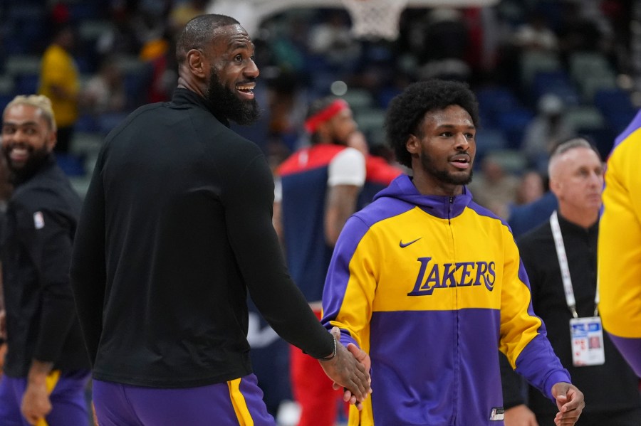 Los Angeles Lakers forward LeBron James greets his son guard Bronny James, right during warm-ups before an NBA basketball game against the New Orleans Pelicans in New Orleans, Saturday, Nov. 16, 2024. (AP Photo/Gerald Herbert)