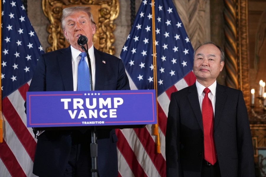 President-elect Donald Trump speaks during a news conference at Mar-a-Lago, Monday, Dec. 16, 2024, in Palm Beach, Fla., as SoftBank Group CEO Masayoshi Son listens. (AP Photo/Evan Vucci)