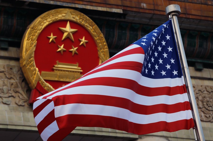 FILE - An American flag is flown next to the Chinese national emblem outside the Great Hall of the People in Beijing, Nov. 9, 2017. (AP Photo/Andy Wong, File)