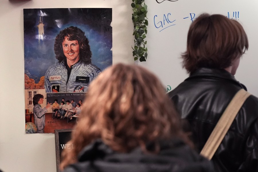 With a poster of NASA's first teacher in space Christa McAuliffe displayed on the wall, students head to their next period class from one of classrooms where McAuliffe taught at Concord High School, Monday, Dec. 16, 2024, in Concord, N.H. (AP Photo/Charles Krupa)