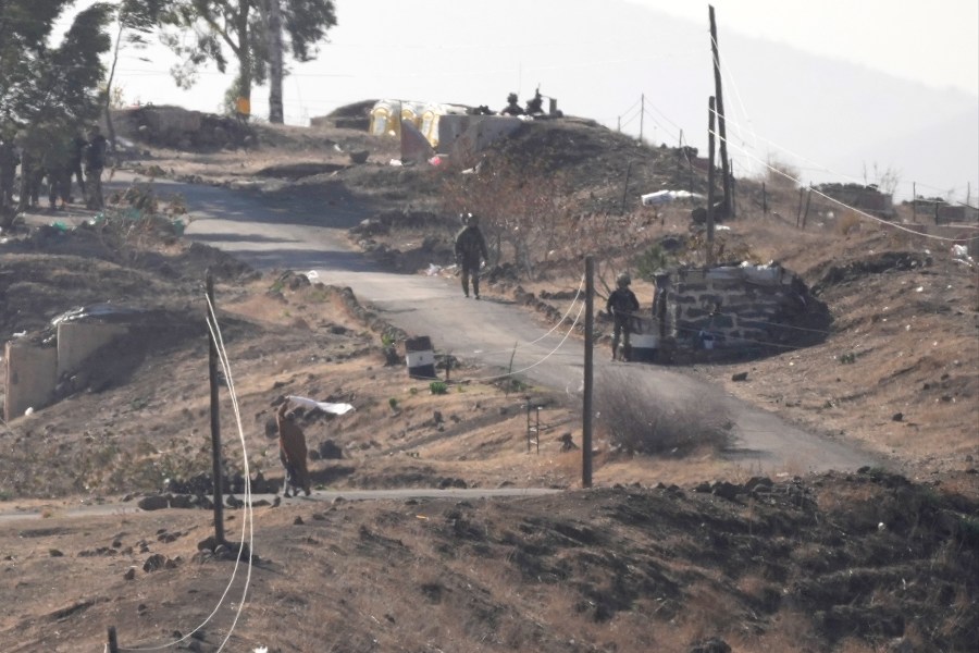 A Syrian man, left, waves a white flag as he approaches Israeli soldiers to negotiate with them, where they set their new position at an abandoned Syrian military base, in Maariyah village near the border with Israel, in southern Syria, Thursday, Dec. 19, 2024. (AP Photo/Hussein Malla)