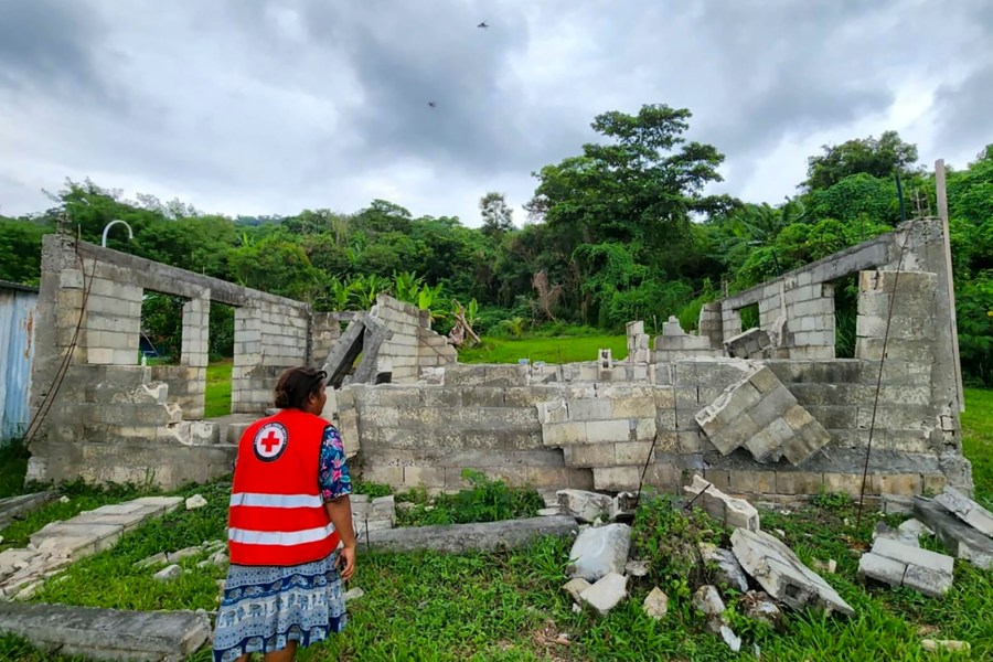 In this photo released by Vanuatu Red Cross Society, a Red Cross volunteer inspects a damaged house in Efate, Vanuatu, Thursday, Dec. 19, 2024, following a powerful earthquake that struck just off the coast of Vanuatu in the South Pacific Ocean. (Vanuatu Red Cross Society via AP)