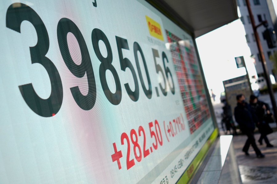 People walk in front of an electronic stock board showing Japan's Nikkei index at a securities firm Friday, Dec. 27, 2024, in Tokyo. (AP Photo/Eugene Hoshiko)